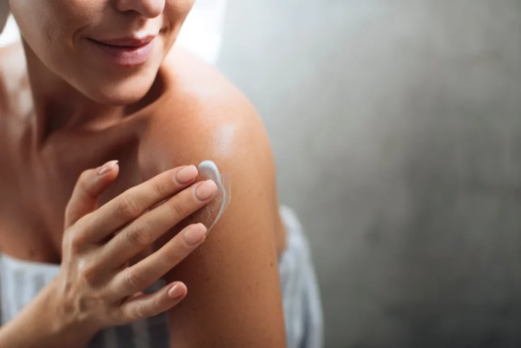 Women applying medical-grade skincare cream on shoulder skin