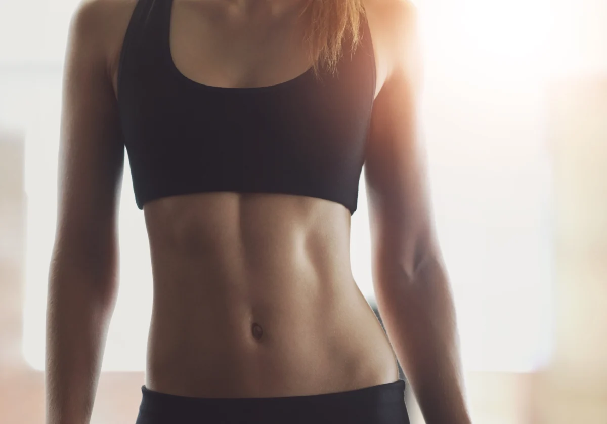 Fit woman showcasing toned abs after body contouring treatment