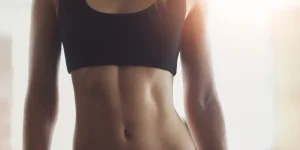 Fit woman showcasing toned abs after body contouring treatment