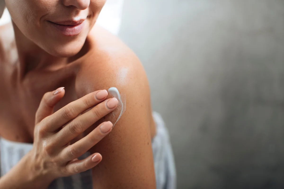 Women applying medical-grade skincare cream on shoulder skin