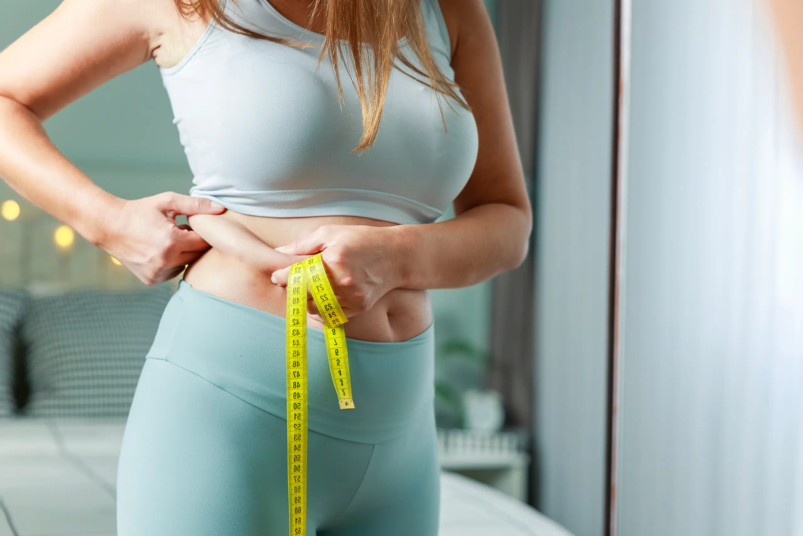 A woman measuring her waist after a successfull excess weight treatment in Sioux Falls, SD